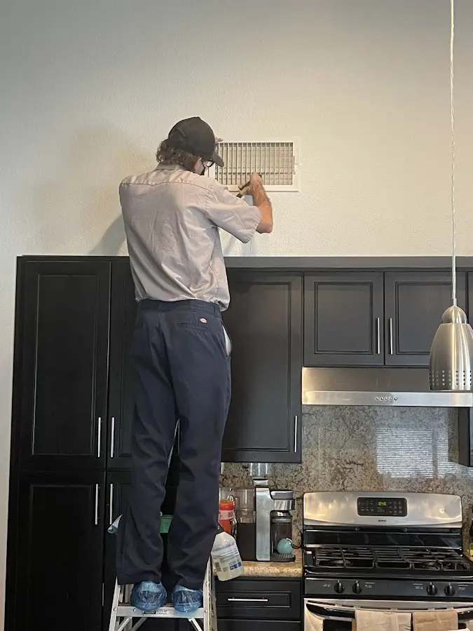 Technician inspecting an air vent during HVAC service in Santee